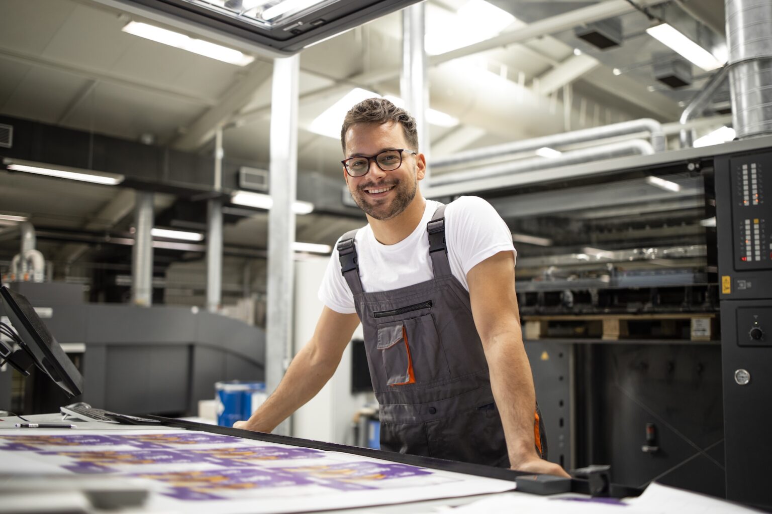 Man smiling with a quality control sheet in a print shop. Industry Resources page image