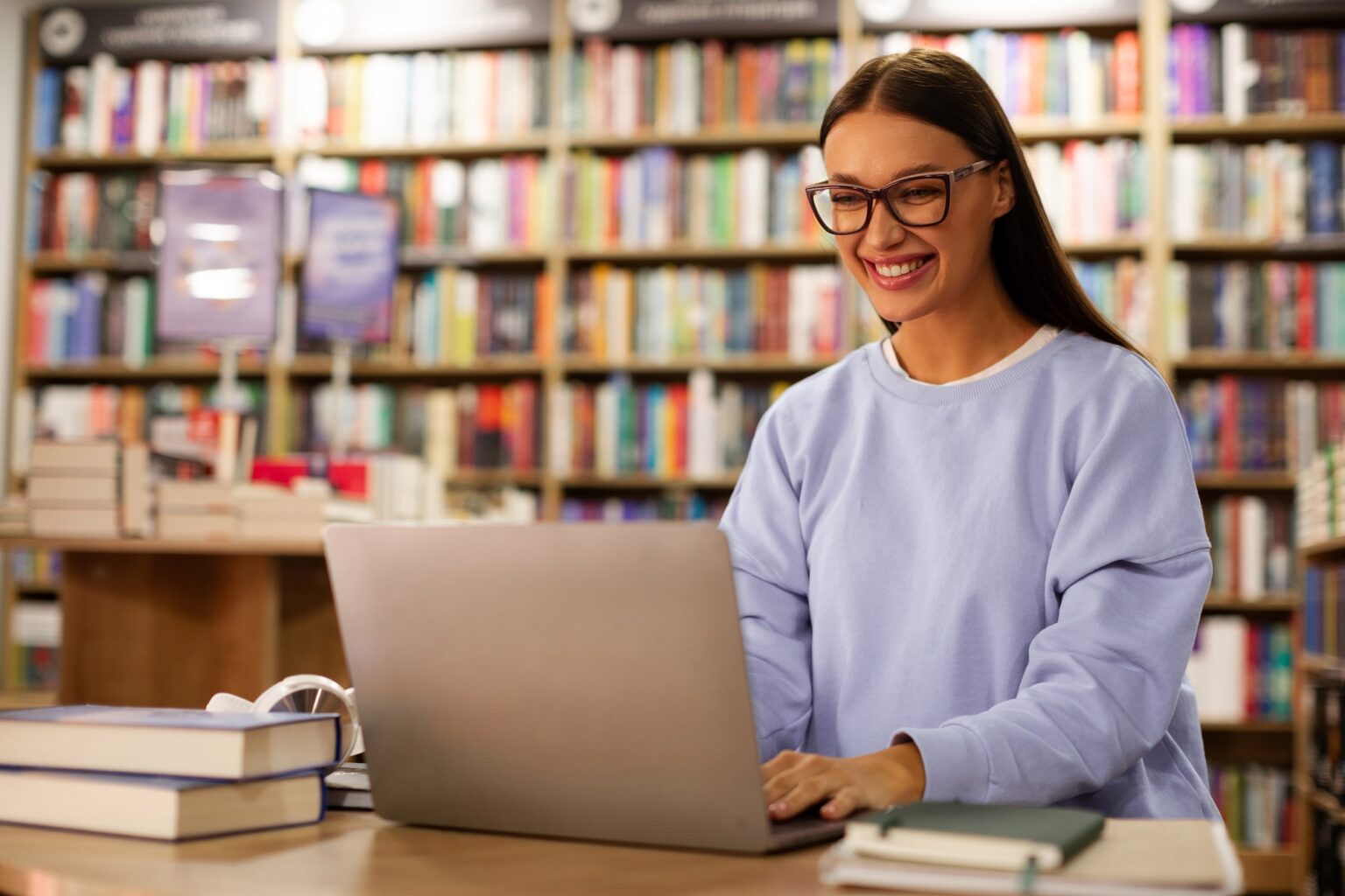 Girl looking at resources on her laptop in a college library