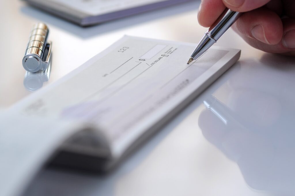 Someone writing a check from a corporation. photo for Industry Resources page and Ways to Give​