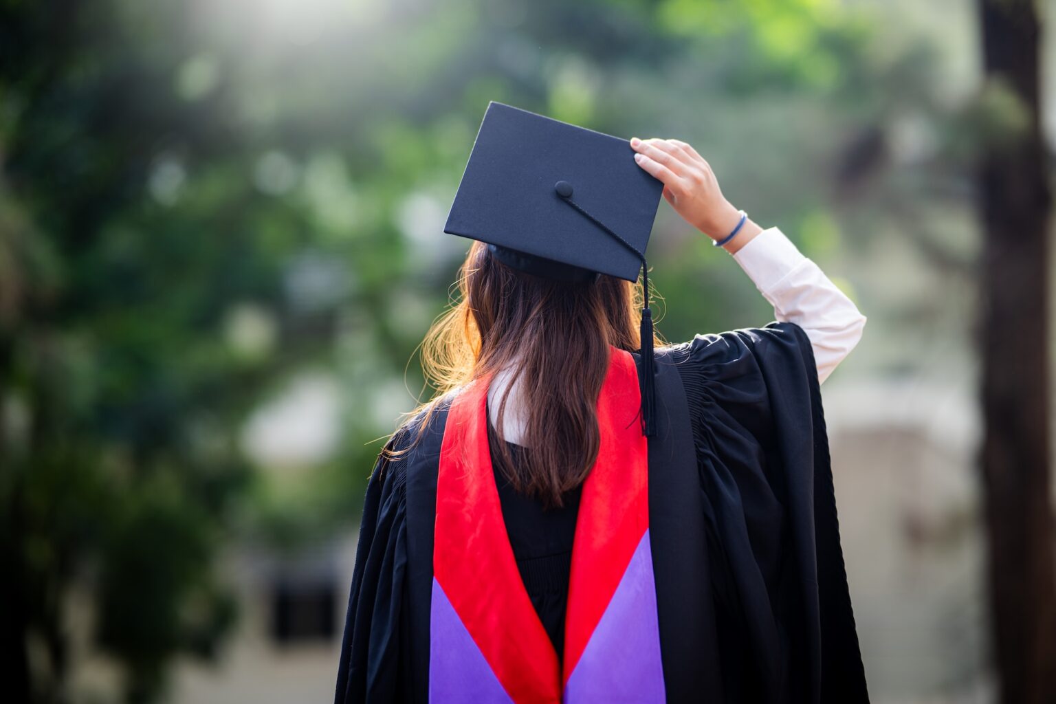 College student in grad cap and gown after using scholarships
